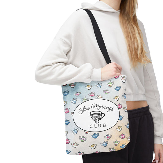 Model holding a 13"x13" tote bag with teacup design and 'Slow Mornings Club' text.