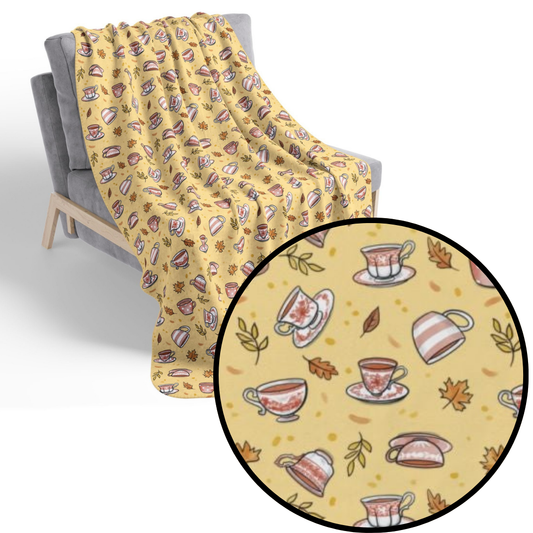 Hand drawn autumn teacups design on a pale yellow fleece blanket draped on a chair with detail call out