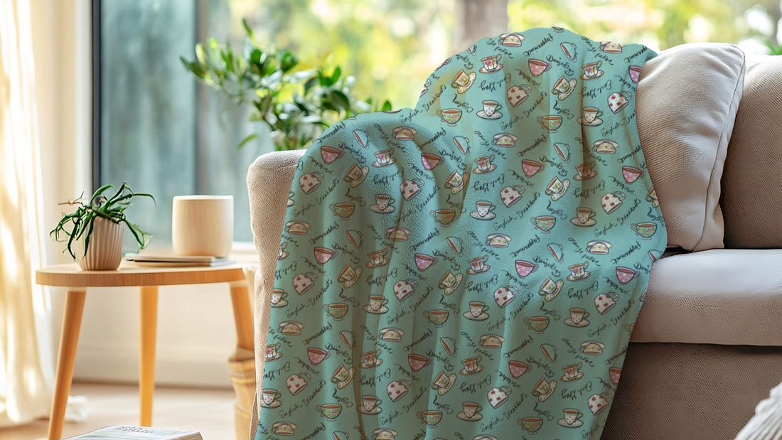 A soft fleece blankets with a colorful teacup pattern  draped on a sofa in a cozy living room.