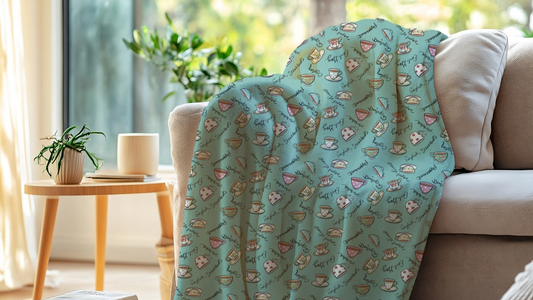 A soft fleece blankets with a colorful teacup pattern  draped on a sofa in a cozy living room.
