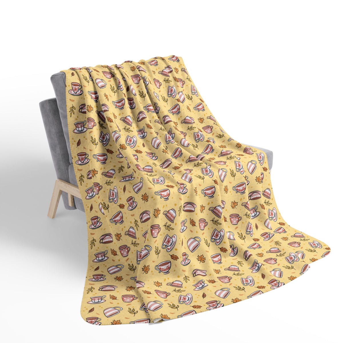Hand drawn autumn teacups design on a pale yellow fleece blanket draped over a chair