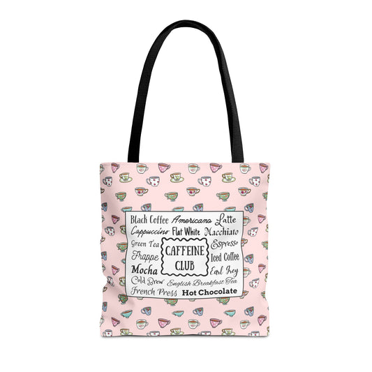 A light pink tote bag with black shoulder straps, featuring a pattern of small hand drawn cups and mugs and  a central white label listing various coffee and tea types.