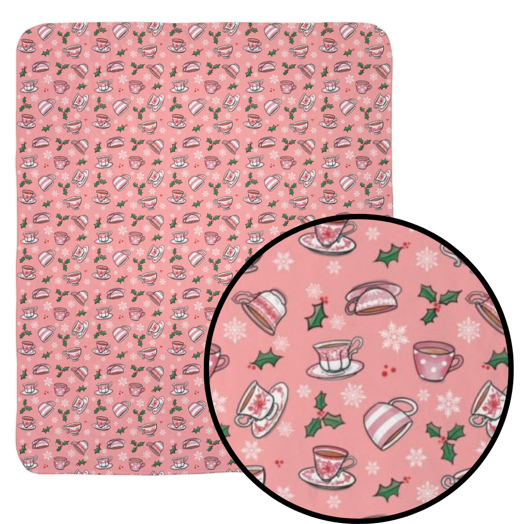 Hand drawn teacups with holly and snowflakes on a soft pink fleece blanket with detail call out