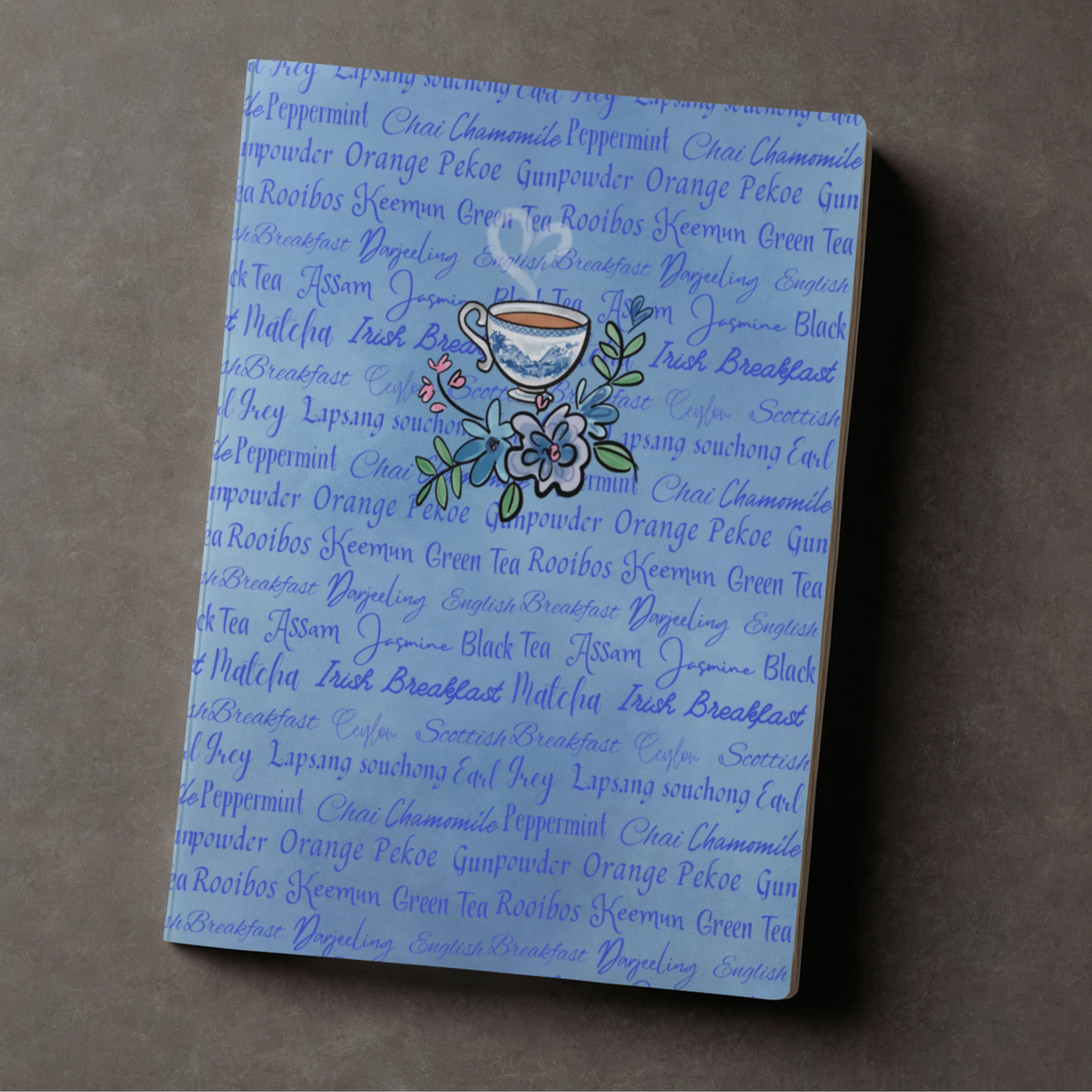 Blue journal with tea type words background design and whimsical hand drawn teacup accent
